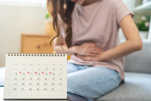 Frau mit den Händen am Bauch neben einem Kalender