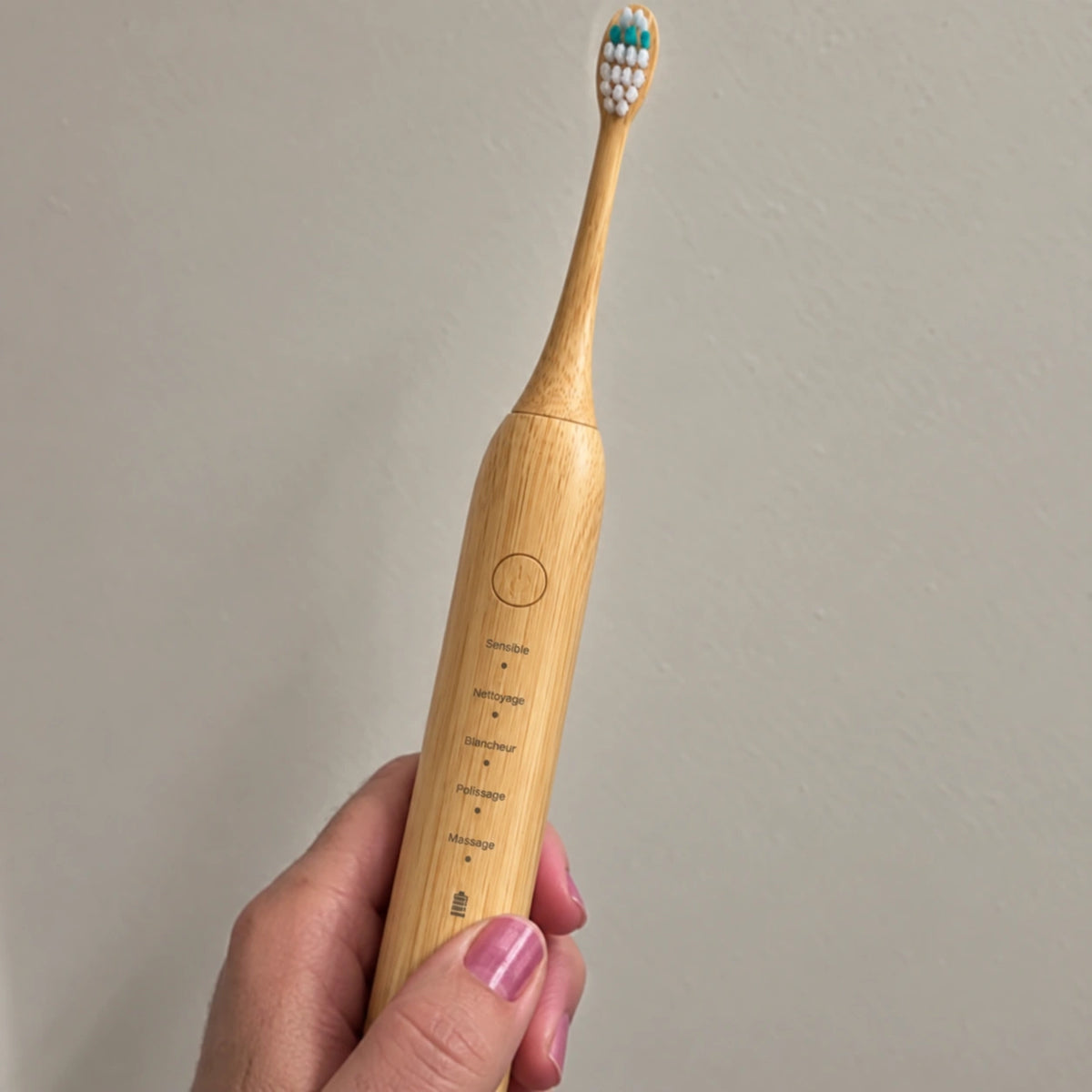 Brosse sonique en bambou tenue dans une main