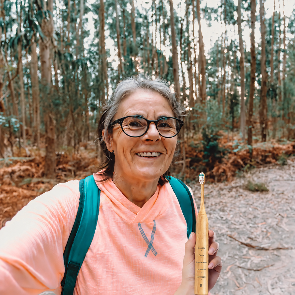 Donna con spazzolino sonico nel bosco